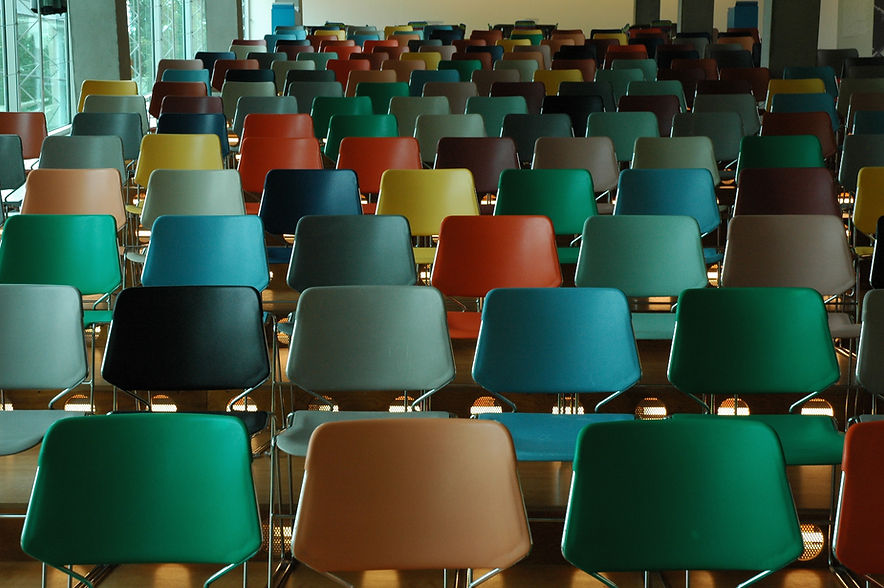 Row of multi colored chairs, green, red, yellow, brown, and blue in lecture hall