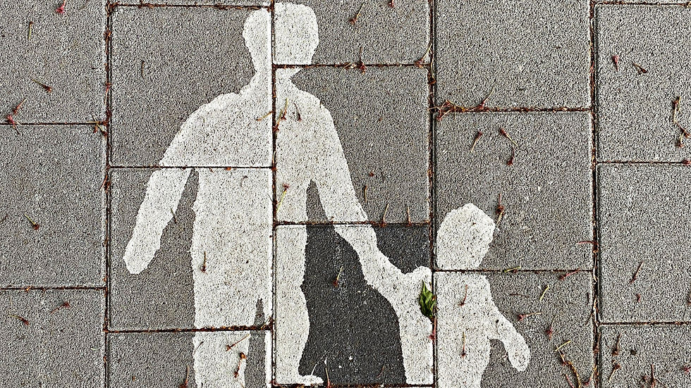 White silhouettes of an adult and child holding hands are painted on gray pavement tiles, with scattered small twigs and debris.