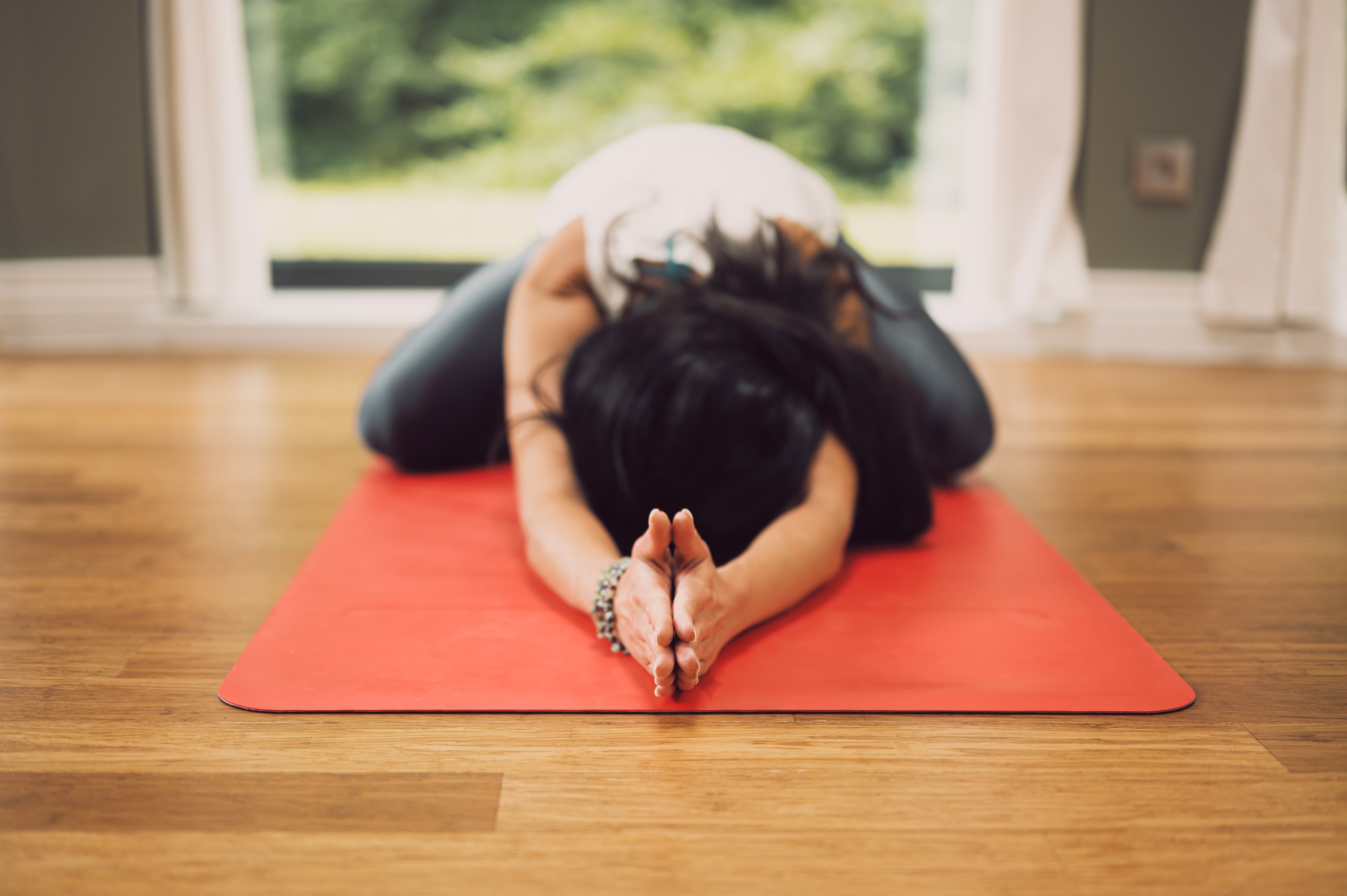 women on red yoga mat in a relaxing pose