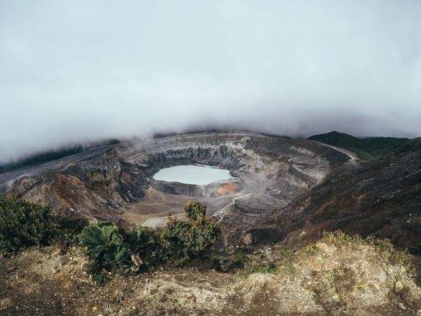 Cratere fumante del vulcano Poás in Costa Rica, avvolto da una nebbia misteriosa.
