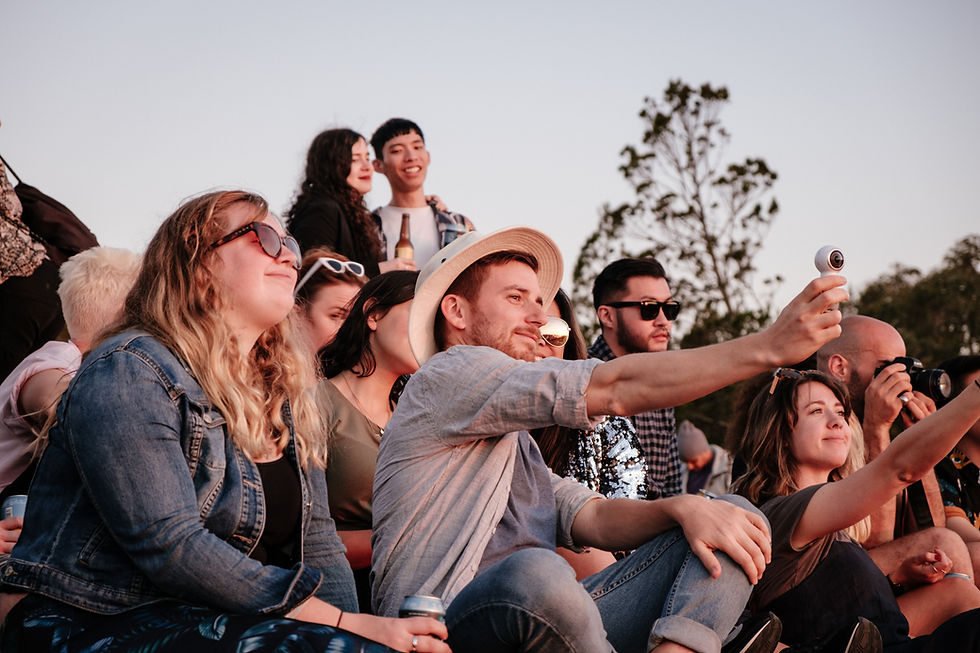 A group of people watching a concert using a 360 camera to livestream the event.