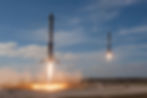 Two SpaceX rockets above a landing pad