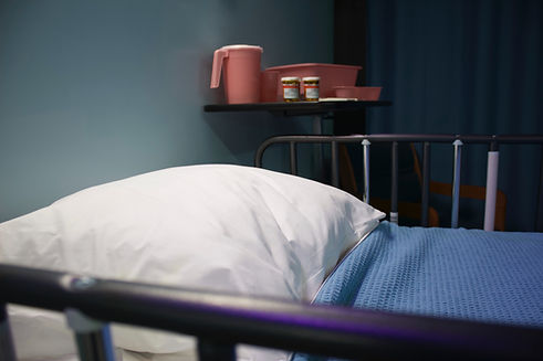 An ampty hospice bed with medication and a water drug on a shelf on the wall. Music therapy for hospice care and bereavement can be held bed side of patients.