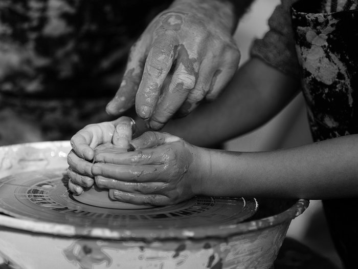 Black and white image of hands shaping clay on a wheel