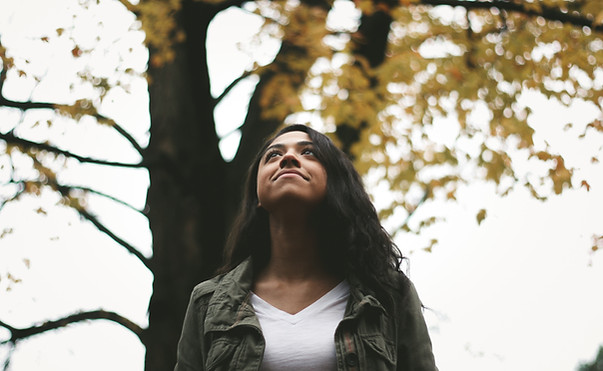 Woman walking with a calm, peaceful expression, captured from head and shoulders — practising mindful walking and grounding through breath and movement.