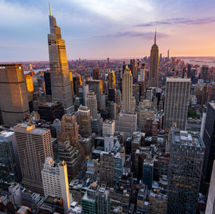 Aerial view of the Midtown Manhattan skyline at sunset, featuring the Empire State Building and surrounding skyscrapers in New York City.