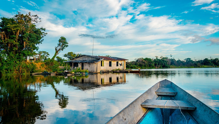 Wooden boat heading towards a hut in the water in the Amazon Jungle Brazil