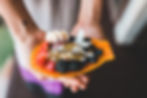 a person holding a papaya decorated with fruit and nuts