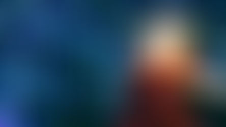 a snow covered street lamp with a red bow around it and holiday lights in the background