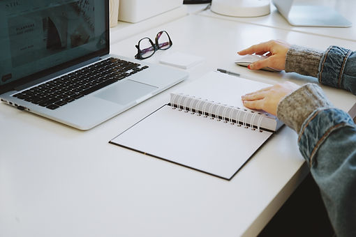 A hand on a notebook with a macbook open belonging to a virtual assistant in Waterloo