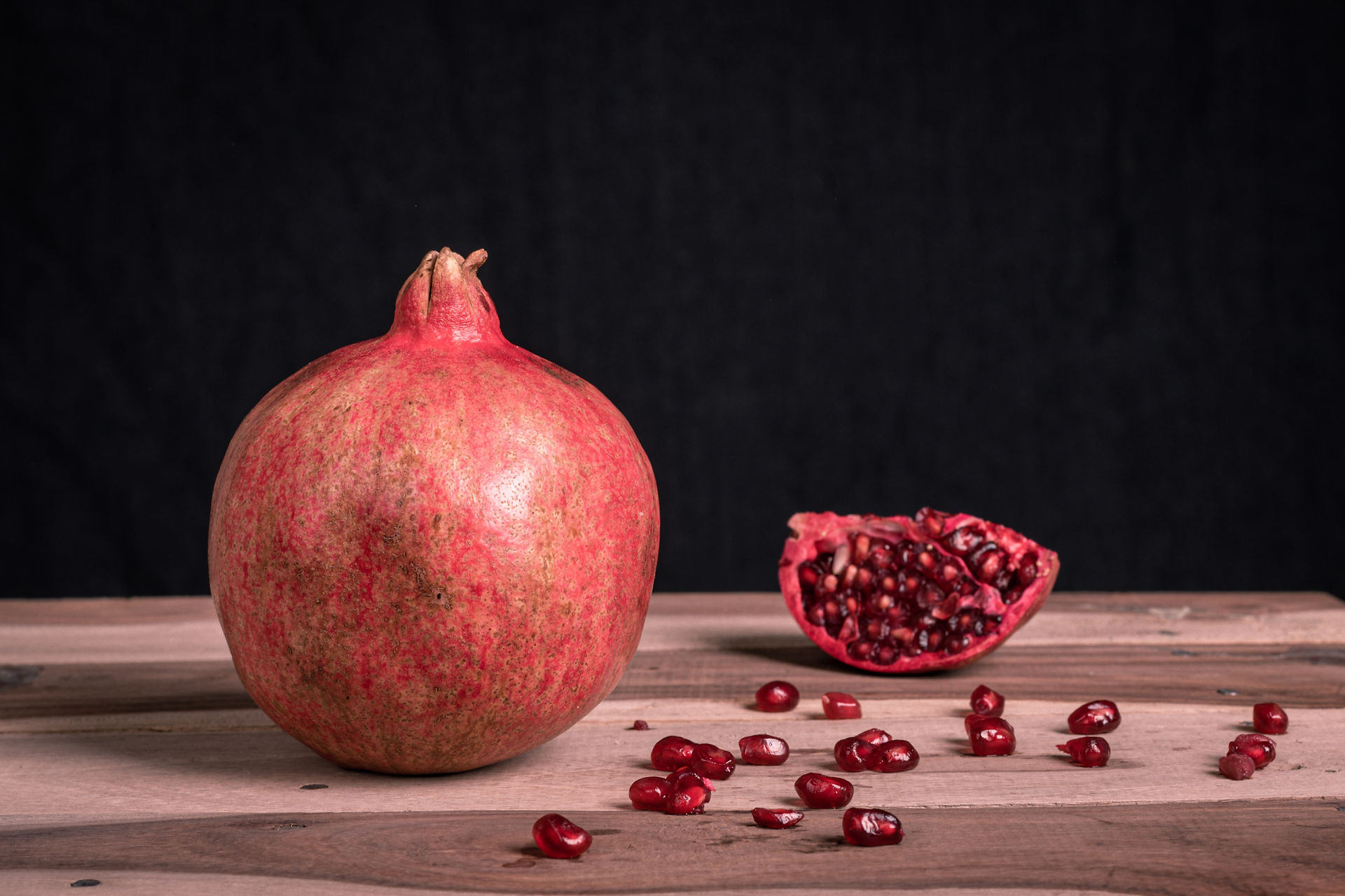 Whole Pomegranate fruit with seeds on a table.