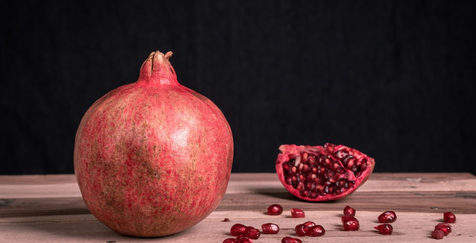 Whole Pomegranate fruit with seeds on a table.