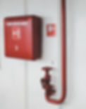 Red fire safety equipment on a white wall includes a box
