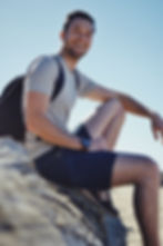 Smiling man sitting outdoors with a backpack