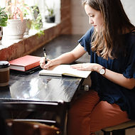 Woman writing in a notebook as she learns how money works