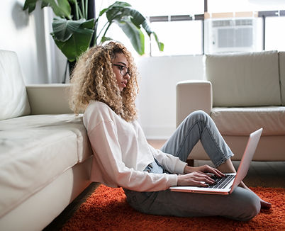 Woman leaning against couch while sitting on floor with her laptop, North Dakota online counseling