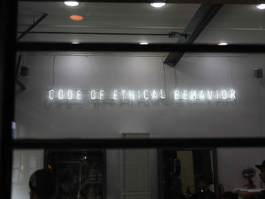 Neon sign on wall says "Code of Ethical Behavior"