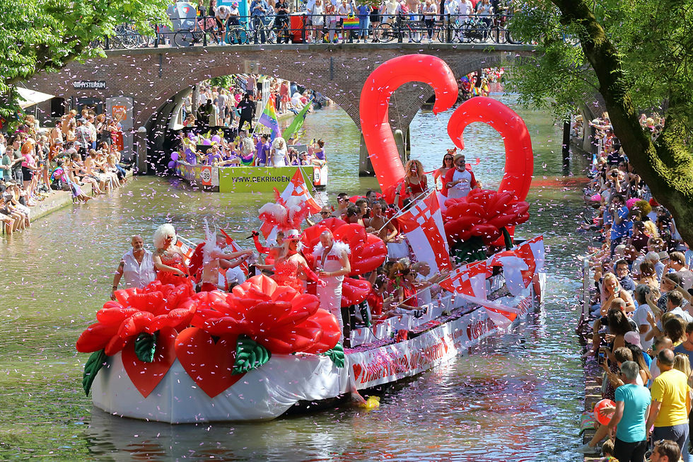 A vibrant parade float adorned with red heart-shaped decorations glides through a crowded canal during the lively festival conducted by Varend Corso Westland.