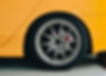 Close-up of a sleek, silver alloy wheel on a bright yellow sports car