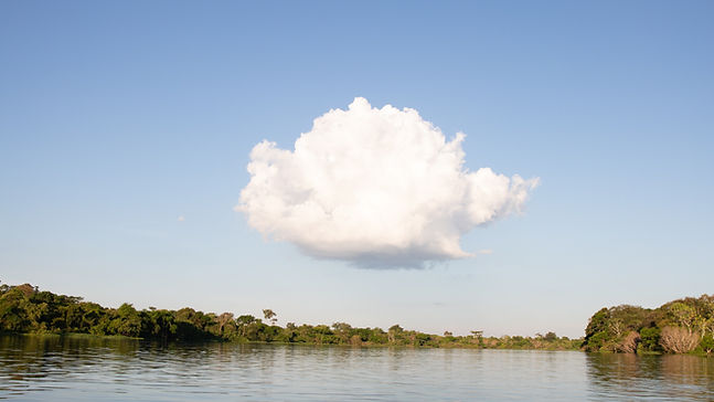 A large cloud in the sky over a river.