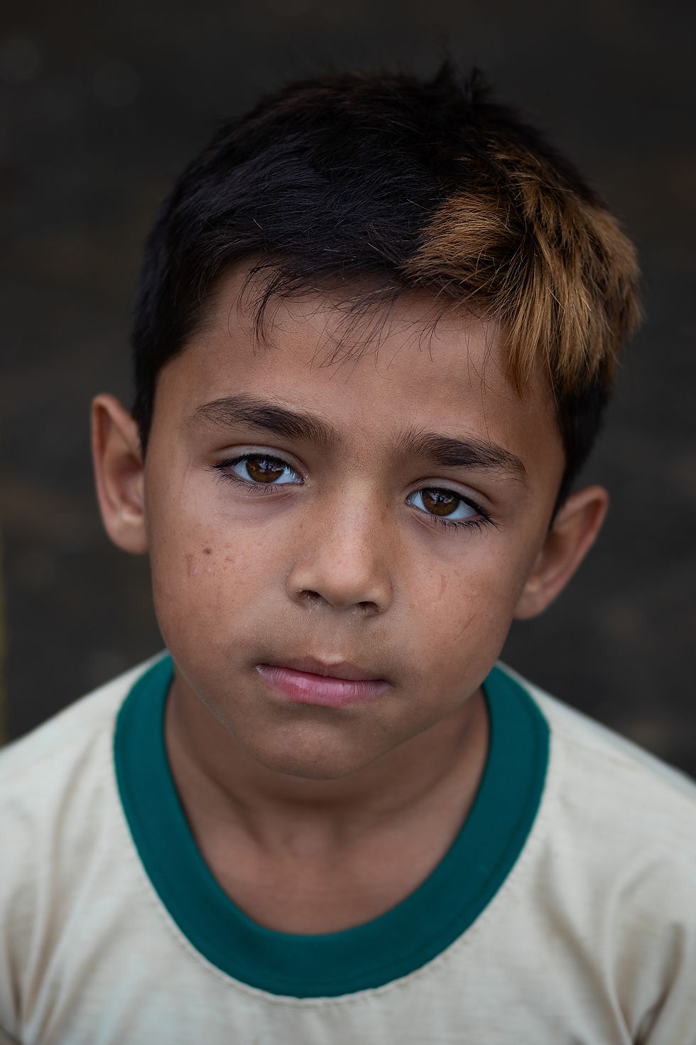 A young boy looks sadly at the camera