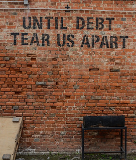 A brick wall with the words 'Until Debt Tear Us Apart stenciled on to it