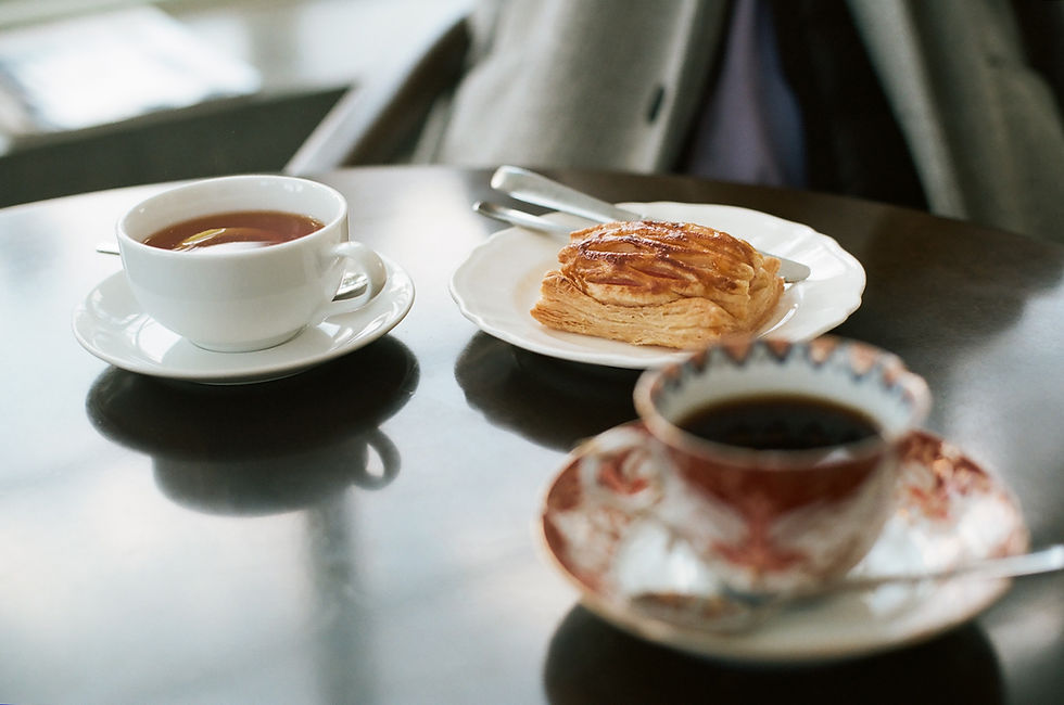 A cozy café setting featuring a steaming cup of tea, freshly brewed coffee, and a flaky pastry, perfect for a relaxing afternoon.