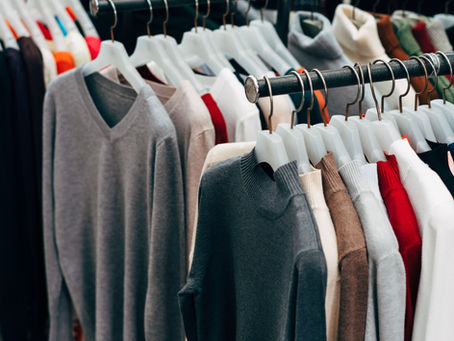Assorted grey, brown, black, and red sweaters and t-shirts hanging on racks – wholesale men’s and women’s clothing collection in Bursa.