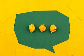 A green speech bubble with yellow scrunched up balls in the middle in front of a yellow background