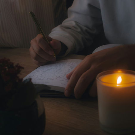 a close up image of a person journaling in candelight
