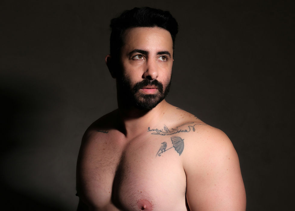 Porträt eines Mannes mit tätowierter Schulter und freiem Oberkörper, beleuchtet im Studio. Die natürliche Hautstruktur steht im Fokus und symbolisiert Hautgesundheit, Selbstbewusstsein und authentische Körperwahrnehmung.