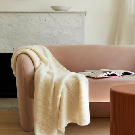 Decorative image of pink couch with a white blanket on top