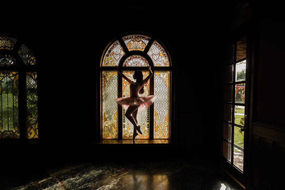 Ballerina leaping in front of stained glass window in dark room demonstrates a positive shift in perspective thanks to an inspirational Oprah quote.