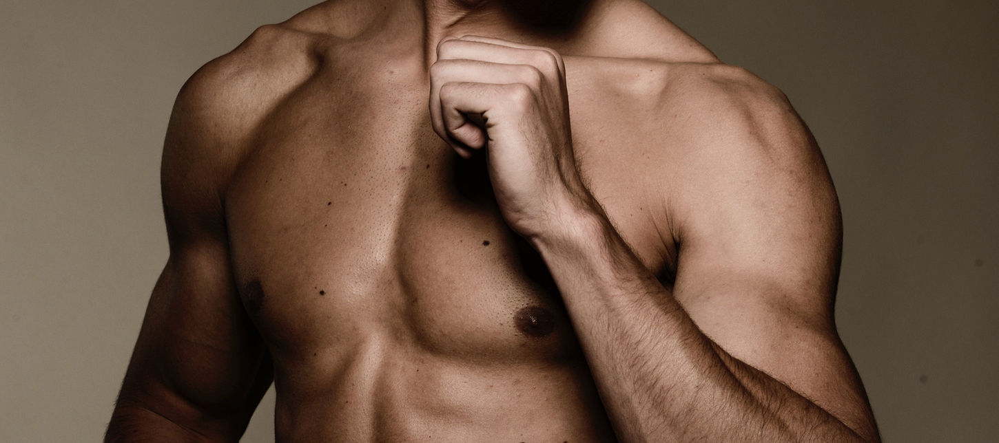 A shirtless muscled man shows his chest, forearms, and biceps.