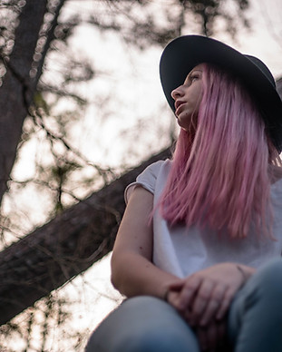 Caucasian woman with pink hair and a hat looking off to the side. Image by Blake Barlow