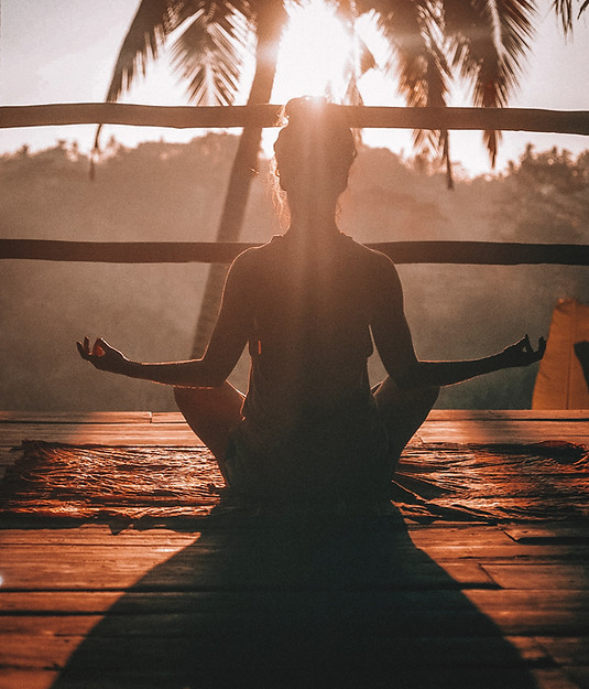 Woman meditation posture in front of a summer view with a palm tree