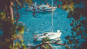 Motor- und Segelboot vor Anker in einer Bucht