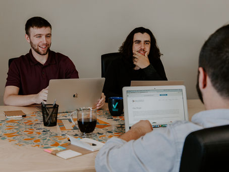 Two colleagues sitting silently at a conference table, avoiding eye contact, representing workplace miscommunication and lack of corporate communication.
