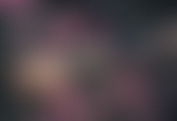 Tattooed arm with an ornate, mechanical design reaches into pink flowers. A silver ring is on the finger. Rustic garden setting.