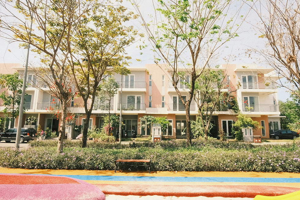 Exterior view of a multi-story condo community with balconies, mature trees, and well-maintained landscaping in Coastal Orange County