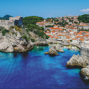 Historic fortress and terracotta-roofed buildings overlooking the azure waters of the Adriatic Sea in Dubrovnik, Croatia.