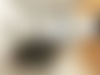 Modern office with two chairs facing a desk, papers and folders organized. Paintings on walls, window view of city, screen displaying text.