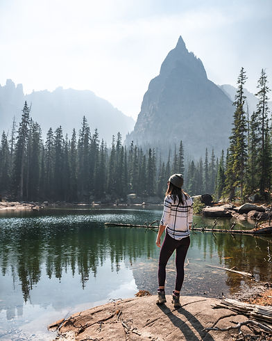 Hipster girl standing beside a lake with Colorado mountains in the background, credit to alyssa teboda