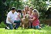 Family outdoors washing a golden retriever dog.