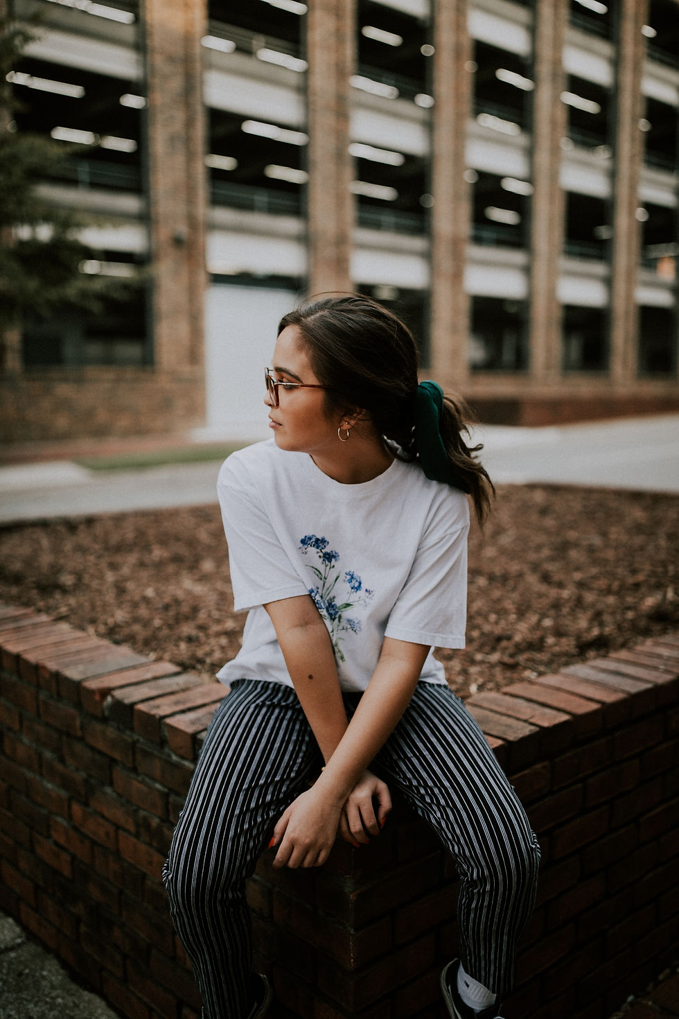 Woman with glasses sitting in city reflecting