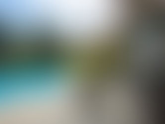 A backyard and patio with a pool and a table with an umbrella and chairs.