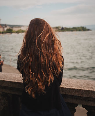 woman with a red long hair looking the river on a bridge