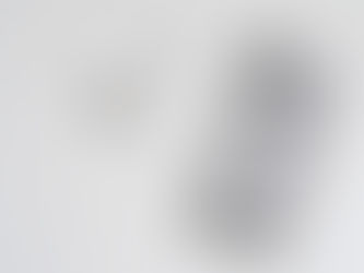 Grey iPhone and white AirPods on a white surface. The iPhone has Apple and "iPhone" logos visible; AirPods are placed near it. Minimalist setting.