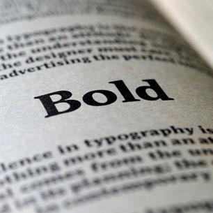 Close-up of a page with the word "Bold" prominently printed in black. Surrounding text slightly blurred. Gray background.