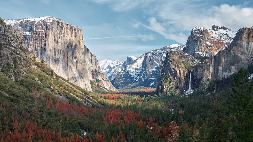 Majestic mountain valley with snow-capped peaks, vibrant red and green forests, and a waterfall. Clear blue sky enhances the serene scene.